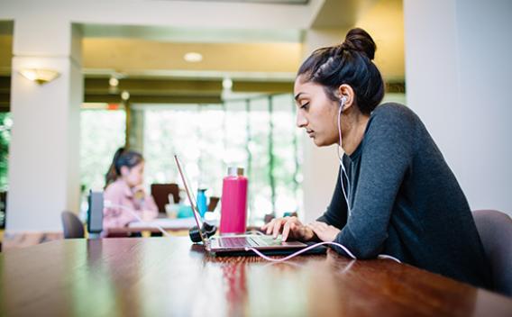 Student sitting at table with headphones and laptop