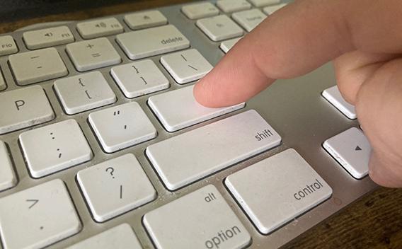 Close-up of a computer keyboard with a person pushing "enter"