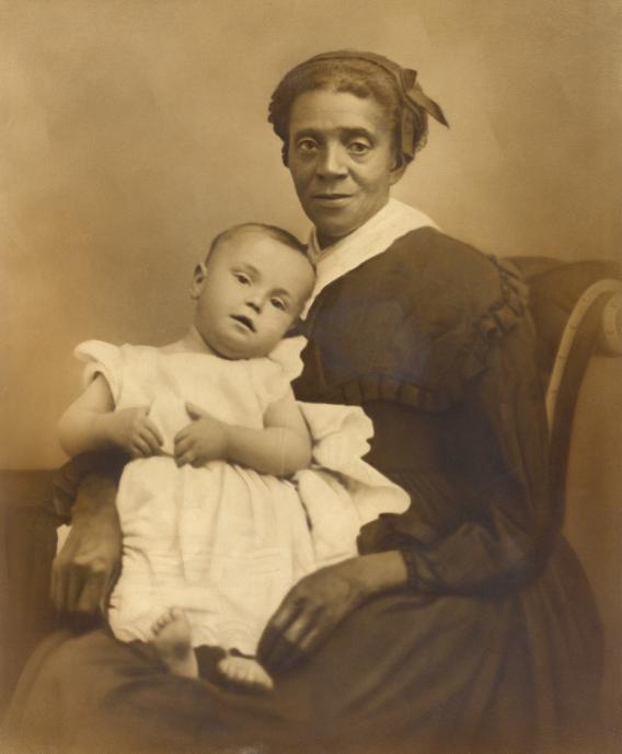 Photo of a black nanny holding a white child.