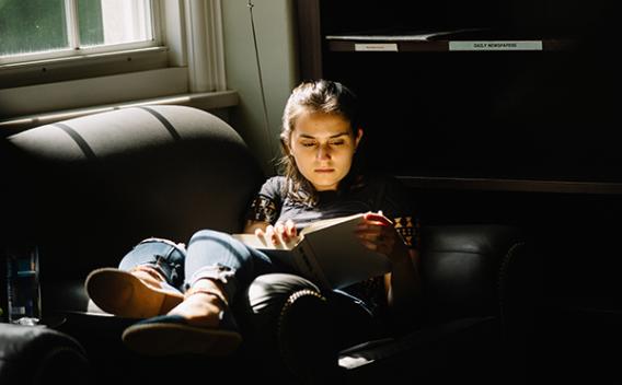 Student reading on a couch in the Matheson Reading Room