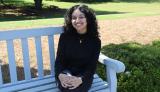 Pakeeza Hameed smiles from a bench outside in a green space